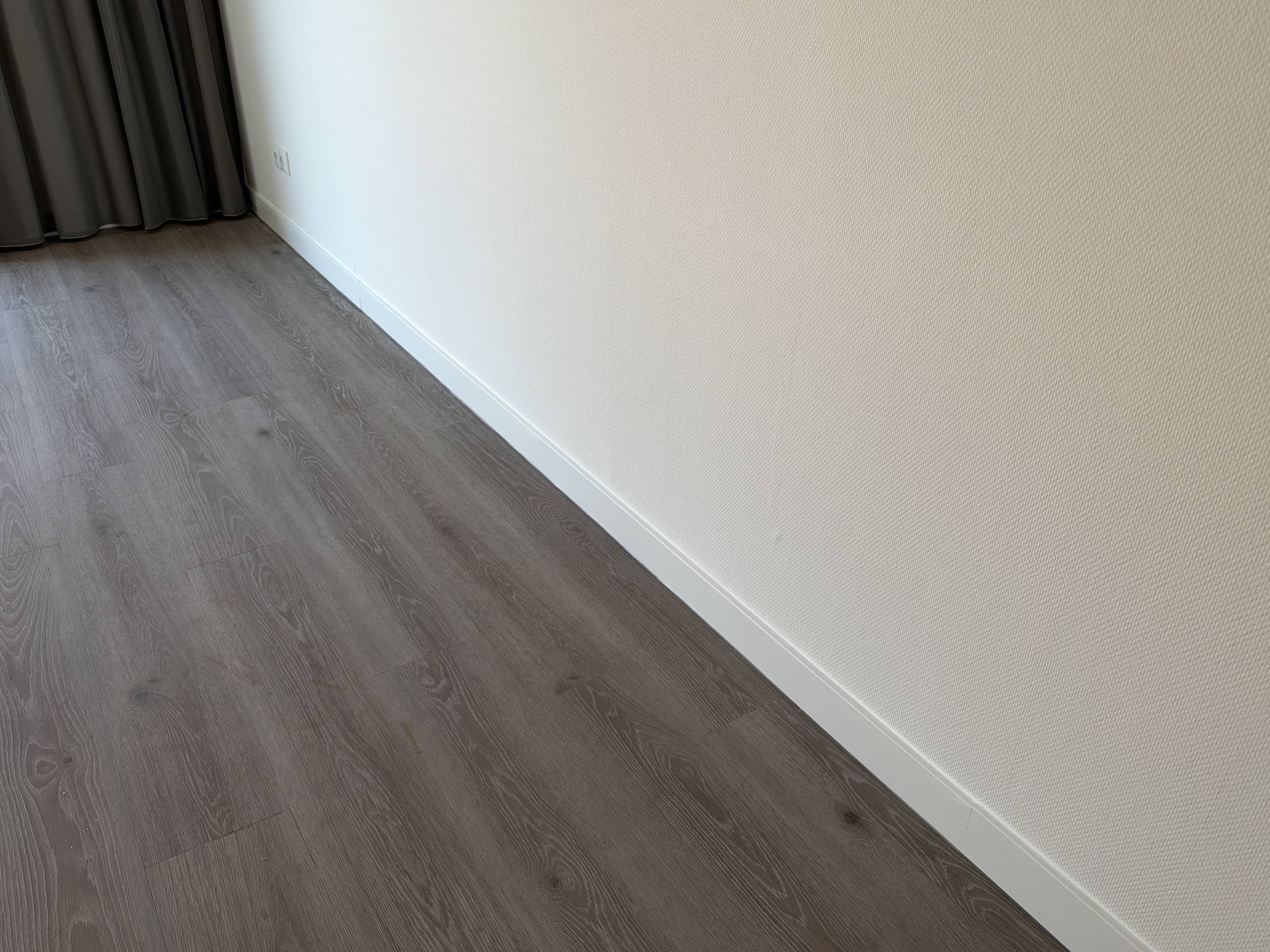 Detail van PVC-vloer en witte plint
